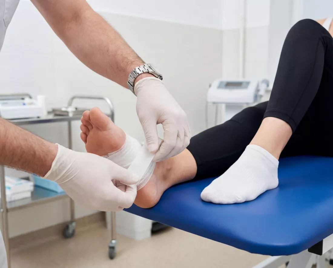 Medico vendando el pie de una paciente en la consulta