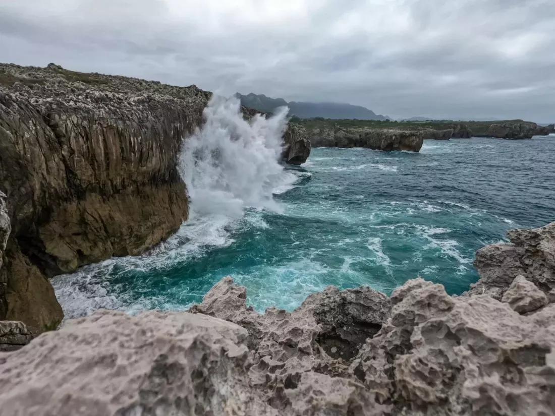 Ola rompiendo contra un acantilado rocoso junto al mar en Asturias