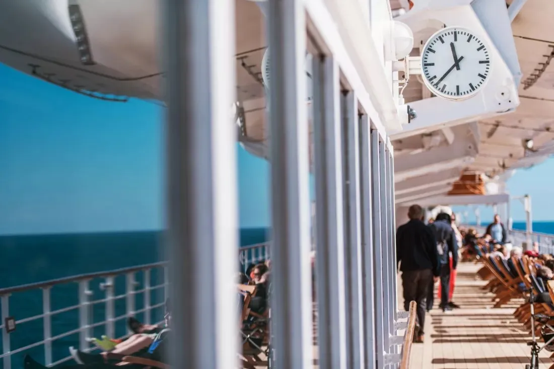Pasajeros pasean por la cubierta soleada de un crucero en alta mar